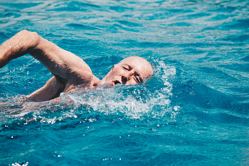 senior man swimming on the blue ocean -health and activity concept