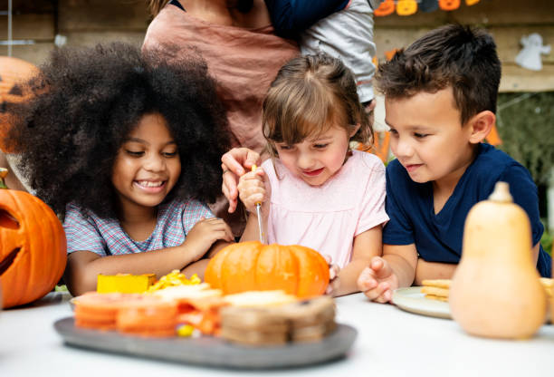 istock Young kids carving Halloween jack-o'-lanterns 1035560632
