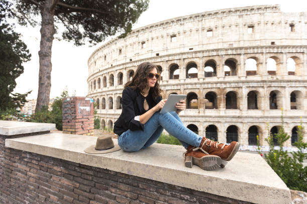 istock Woman sitting in front of Coliseum and using tablet 1035561434