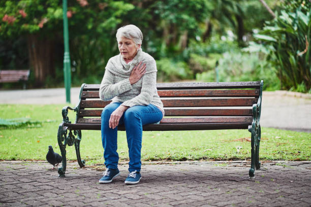 Something doesn’t feel right… Shot of a senior woman suffering from a heart attack in the park senior adult women park bench 70s stock pictures, royalty-free photos & images