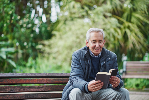 Shot of a senior man reading a book and relaxing in the park