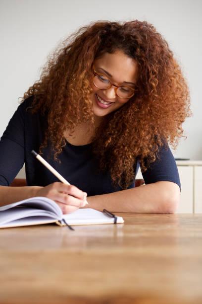istock happy young woman with glasses writing in book 1035624972