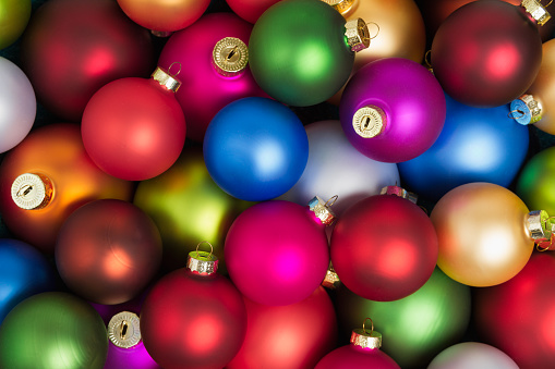 A heap of colorful christmas baubles lying on the floor in flat lay.