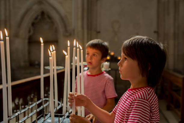petit garçon prie et met une bougie dans l’église orthodoxe - church altar indoors dark photos et images de collection