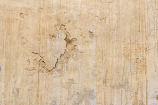 istock Weathered yellow painted wall background, partially faded 1035640290