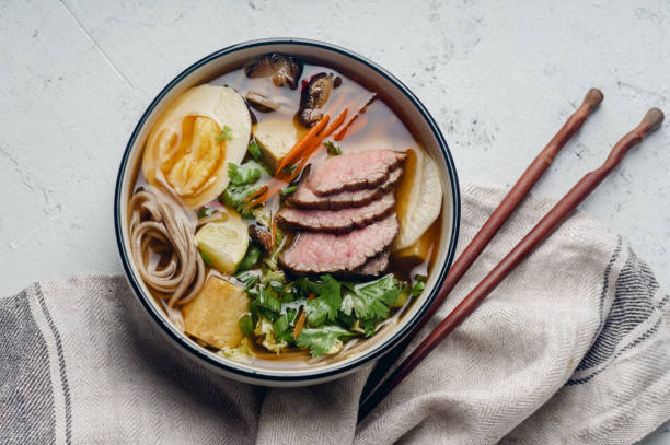 Miso ramen with roasted beef, shiitake mushrooms, fried tofu, leek and eggs on concrete background. Top view. Lunch in asian style Miso ramen with roasted beef, shiitake mushrooms, fried tofu, leek and eggs on concrete background. Top view. Lunch in asian style stew photos stock pictures, royalty-free photos & images