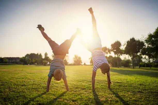 Photo of Brother and sister standing on hands on grass
