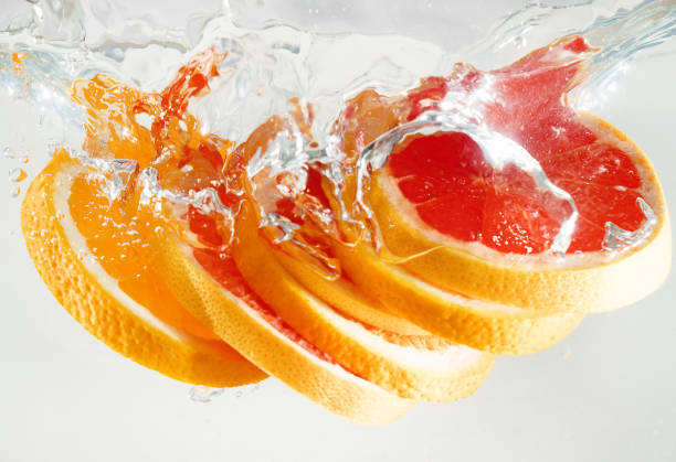 istock Grapefruit and orange falling to the water. Suitable for advertisement. 1035650476