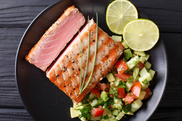 istock Lime Grilled Tuna with Avocado Cucumber Salsa closeup on a plate. Top view from above horizontal 1035653490