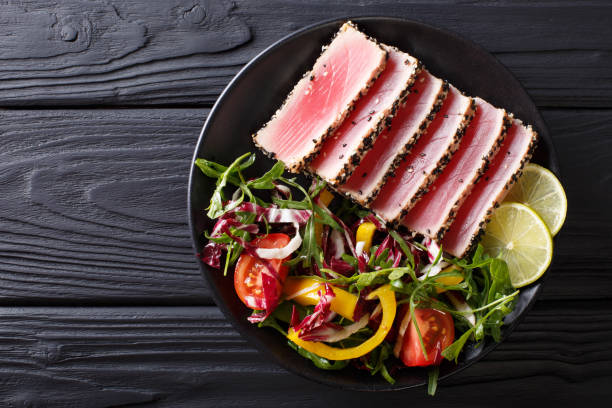 新鮮な野菜サラダのまれなたたきマグロ マグロ スライスのクローズ アップ。トップ ビューの水平 - peppered tuna ストックフォトと画像