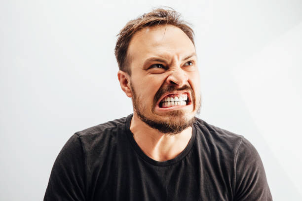 Portrait of clenching teeth mid adult man Portrait of clenching teeth mid adult man clenching teeth stock pictures, royalty-free photos & images