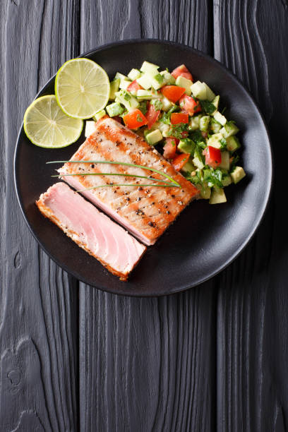 istock Freshly cooked grilled tuna steak with avocado cucumber salsa close-up. Vertical view from above 1035659748