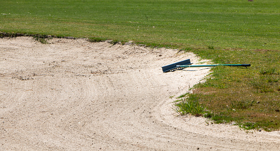 view of sand rake lying in a bunker on a golf course