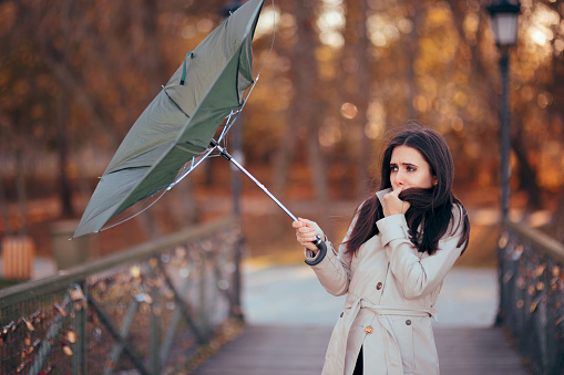 Chica lucha contra el viento sosteniendo paraguas llueve el tiempo en photo