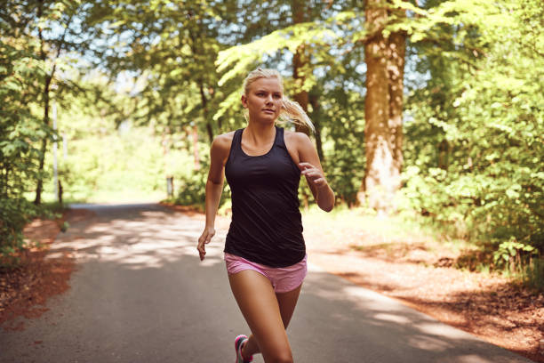 istock Fit young woman jogging alone on a forest path 1035668456