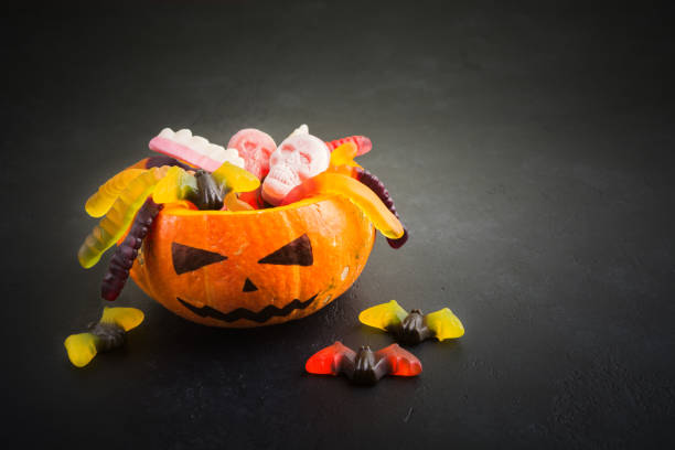 istock Pumpkin Jack with Halloween candies (worms, skulls, bats) on black background 1035678956
