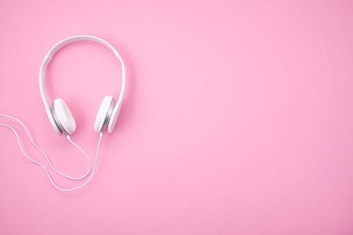 White earphones on pink background with copy space