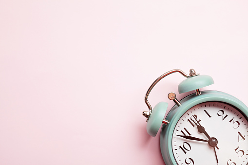 Retro style alarm clock over the pastel pink background