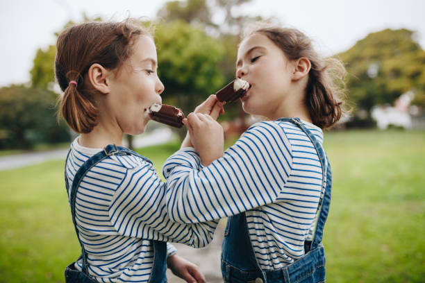 istock Twin sisters enjoying eating candy icecream 1035682574