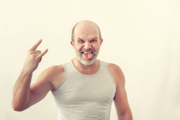 istock Adult man with gray beard, shows tongue, gesture with hand horn 1035683036
