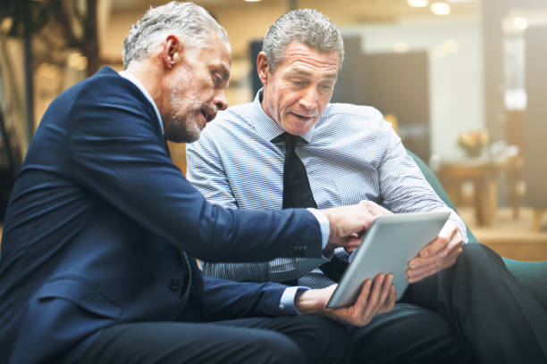 istock Two mature businessmen discussing work on a digital tablet 1035688092