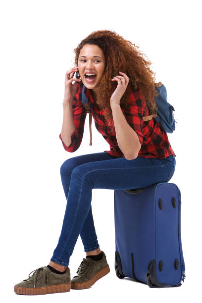 istock happy young woman talking on mobile phone while sitting on suitcase by isolated white background 1035689410