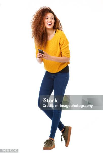 Full Body Happy Woman With Cellphone Laughing Against Isolated White Background Stock Photo - Download Image Now