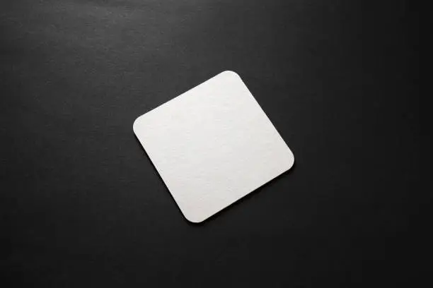 Blank square beer coaster mockup on black background.