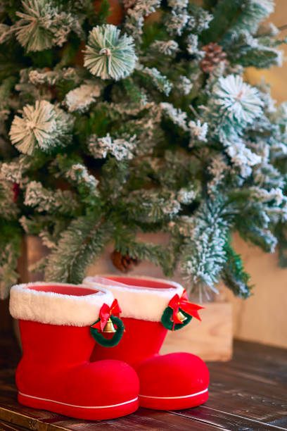 istock Red with white border Christmas boots under Christmas tree on wooden background 1035708446