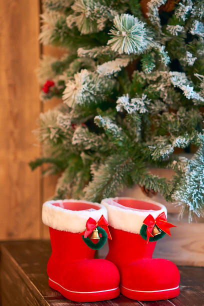 istock Red with white border Christmas boots under Christmas tree on wooden background 1035708464