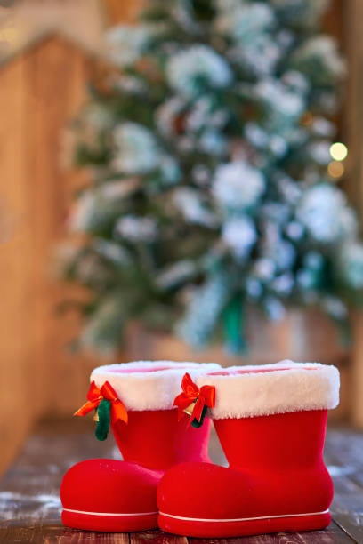 istock Red with white border Christmas boots under Christmas tree on wooden background 1035708494