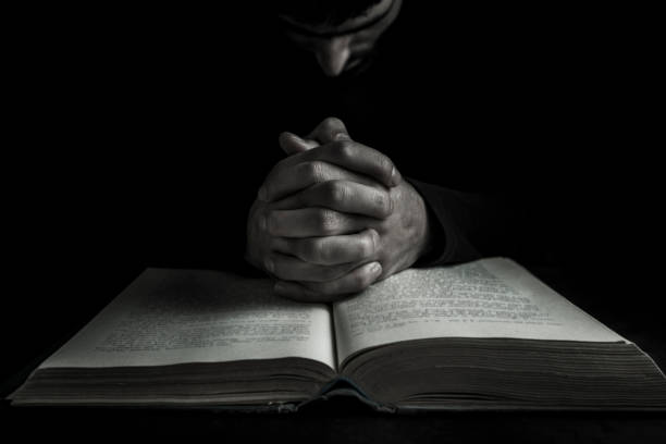 istock Hands of a human in prayer on a Holy Bible 1035726034