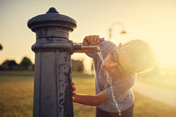 istock Little boy drinking water from public fountain 1035729574