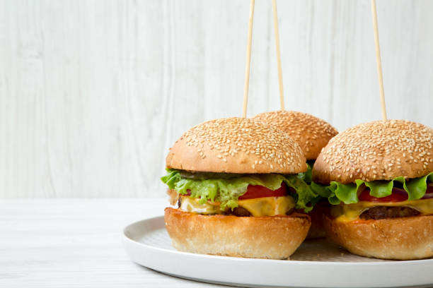 istock Cheeseburgers on grey plate. White wooden background. Side view. Close-up. Copy space. 1035740392
