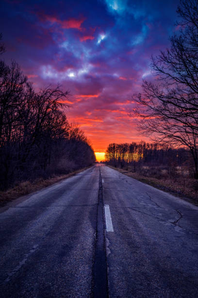 Amazing colorful sunrise with dramatic clouds on the road in the winter