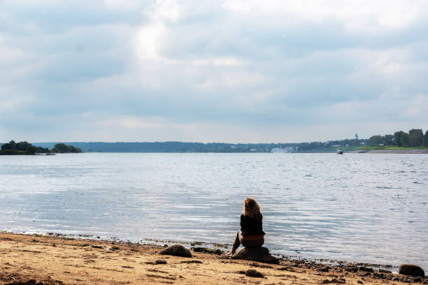 istock A girl sits on the river bank. 1035743126