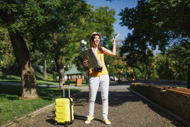 Concerned traveler tourist woman in hat with suitcase and city map spreading hands looking away walking in city outdoor. Girl traveling abroad to travel on weekends getaway. Tourism journey lifestyle mujer de turista viajero interesado en sombrero con maleta y difusión del mapa de la ciudad de las manos mirando lejos caminando en la ciudad al aire libre. muchacha de viajar al extranjero para viajar de escapada de fin de semana. vida de viaje de turism