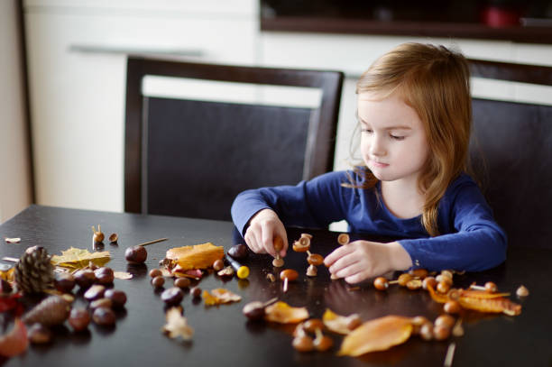 menina fazendo criaturas castanhas - child autumn craft preschooler - fotografias e filmes do acervo