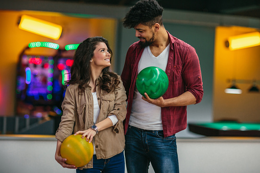 Shot of a attractive young couple holding bowling balls