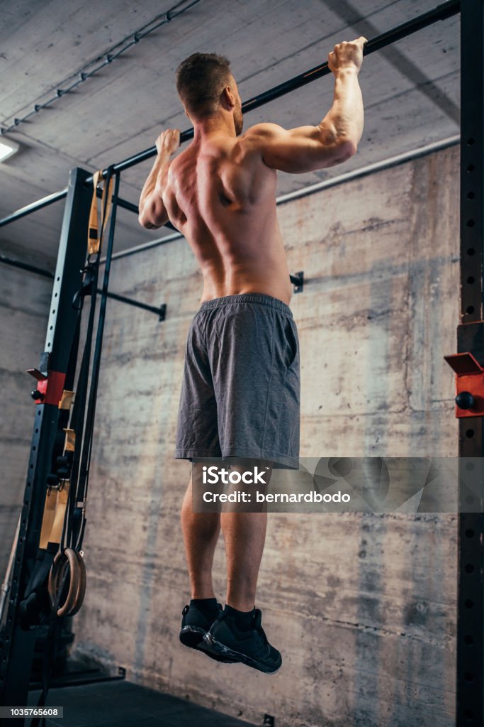 Getting stronger day by day Rear view of a man doing pull-ups at the gym Adult Stock Photo