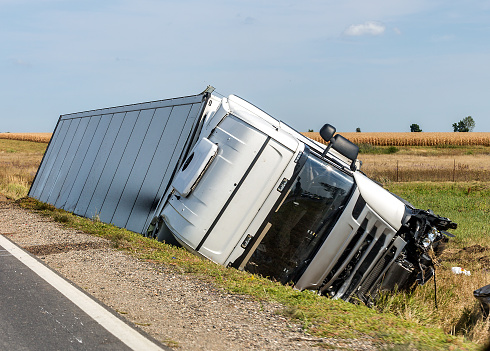 The large truck lies in a side ditch after the road accident.