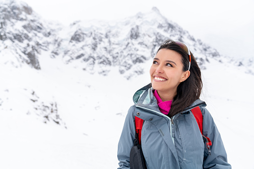Portrait of a thoughtful woman trekking in the snow mountains and looking very happy smiling