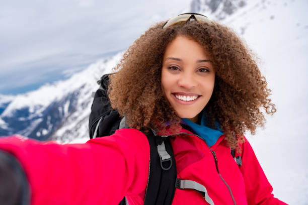 Happy woman taking a selfie while trekking in the snow
