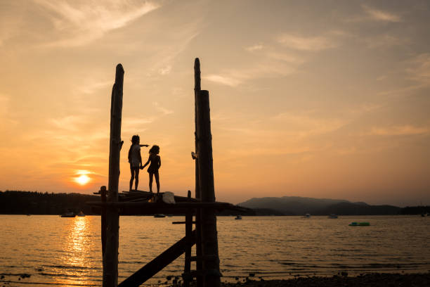 A couple is walking on a beach at sunset, with the man carrying the woman on his back. Scene is romantic and peaceful, as the couple enjoys the beautiful sunset and each other's company