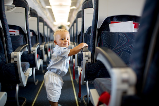Little baby boy, playing with toys on board of the aircraft, happy traveler