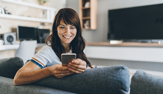 Mujer enviando mensajes de texto en su hogar en el teléfono photo