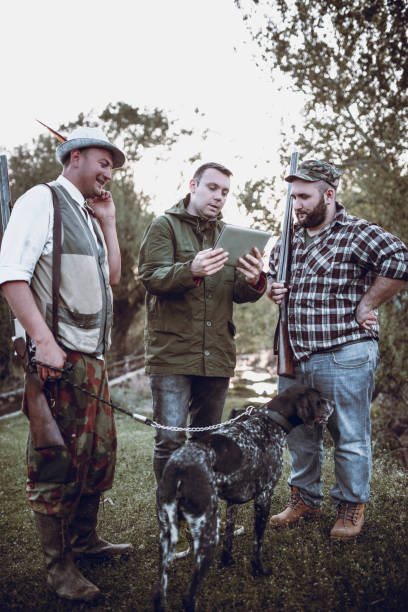 istock Group of Hunters with Dog Looking for GPS Coordinates on Tablet in Nature 1035783432