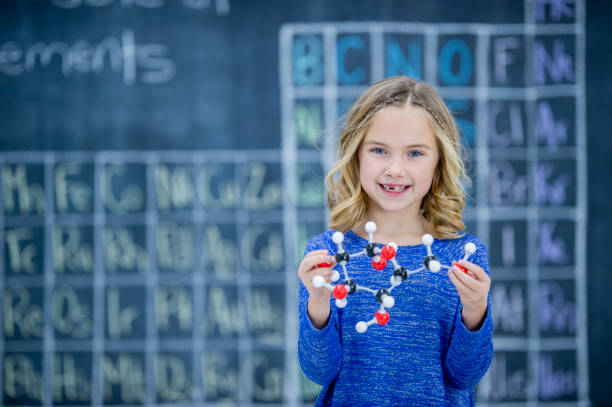 istock A young girl smiles at the front of a class with a molecular model in her hands 1035784052