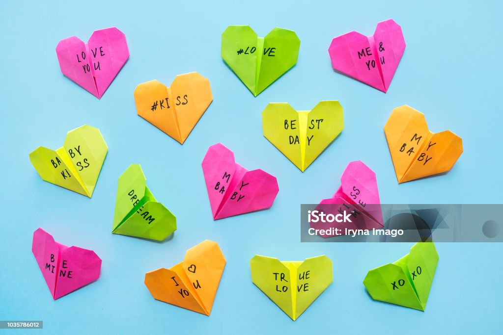 Cuori Di Origami Di Carta Brillante Multicolore Con Testo Love You Bacio  Bambino Sii Mio Molti Cuori Geometrici Di San Valentino Rosa Arancione  Giallo Verde Carta Origami Su Sfondo Blu - Fotografie