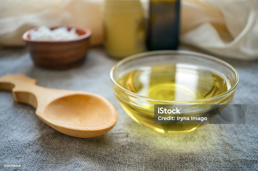 Liquid coconut MCT oil in round glass bowl with wooden spoon and bottles. Health Benefits of MCT Oil. Triglycerides, a form of saturated fatty acid. Cooking Oil Stock Photo